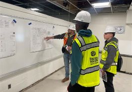  two students wearing construction hat and safety vest with mentor